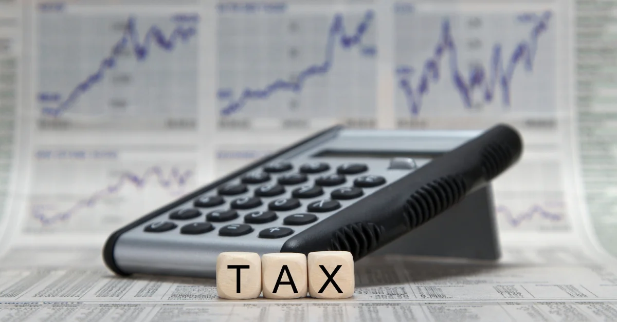 Image of Calculator placed on financial charts with wooden blocks spelling TAX, representing corporate tax registration and financial compliance.