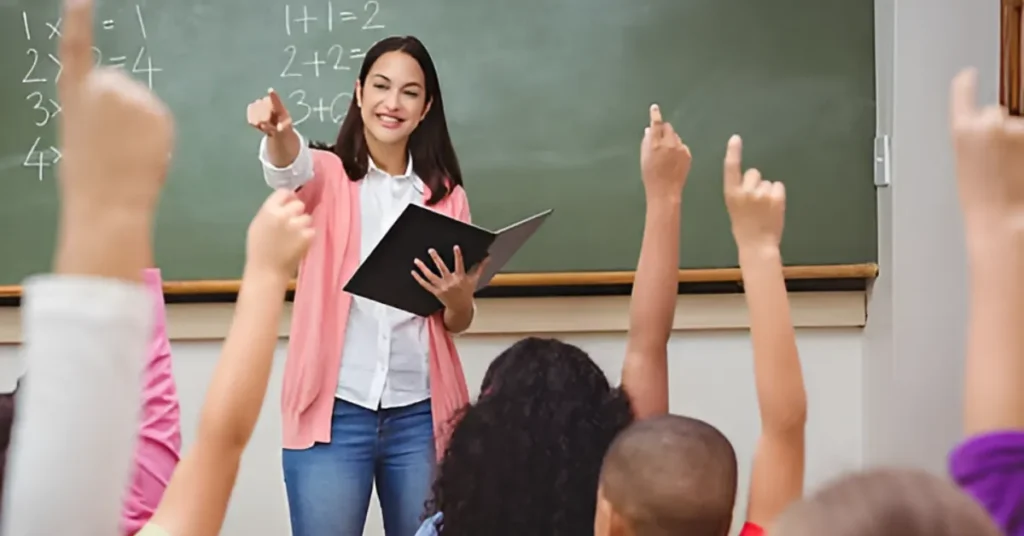 Teacher checking UAE licensing portal on laptop in classroom setting.