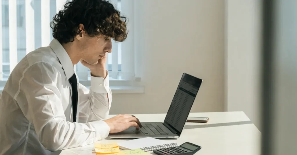 Young entrepreneur researching Low Cost Business Ideas and preparing a business plan before launching a startup.